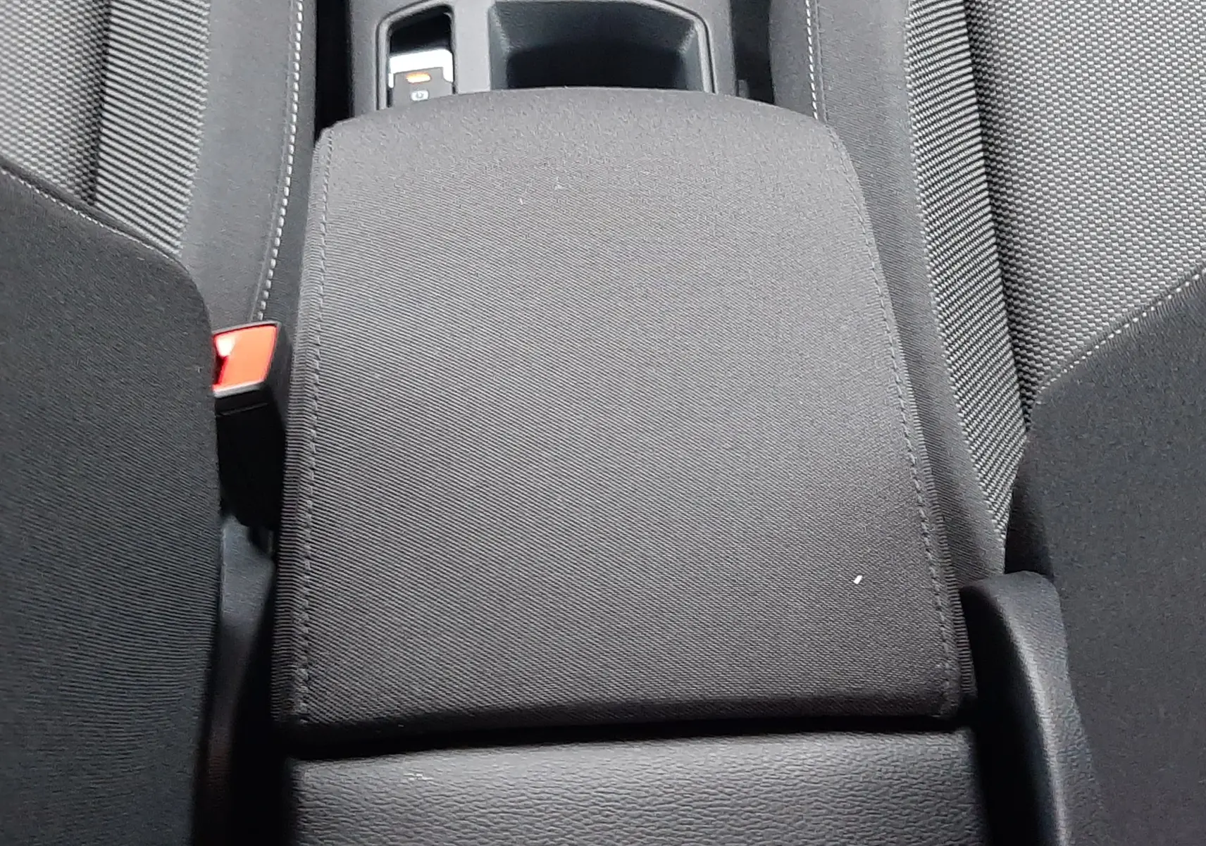 Vue rapprochée de l'accoudoir central noir entre les sièges avant du Volkswagen T-Roc 1.5 TSI 2025.