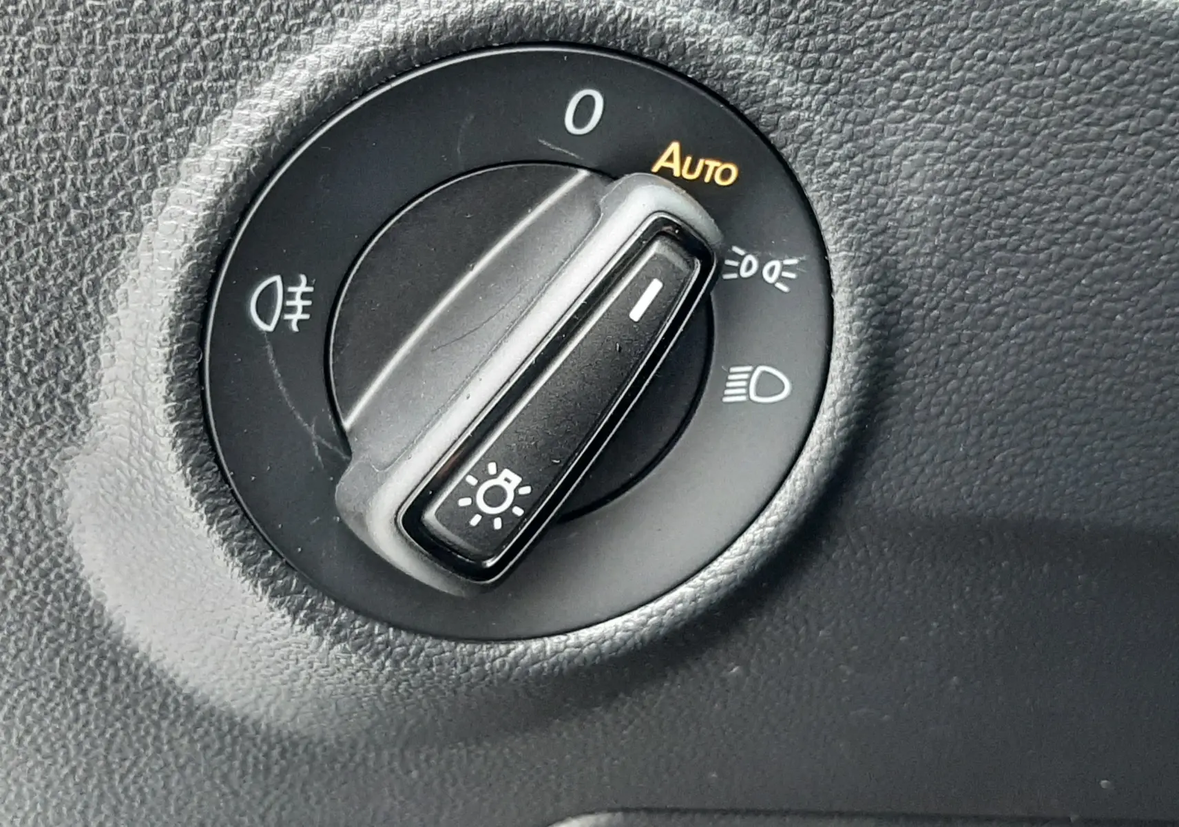 Gros plan sur le sélecteur de phares noir dans l’habitacle du Volkswagen T-Roc gris pyrite 2025.