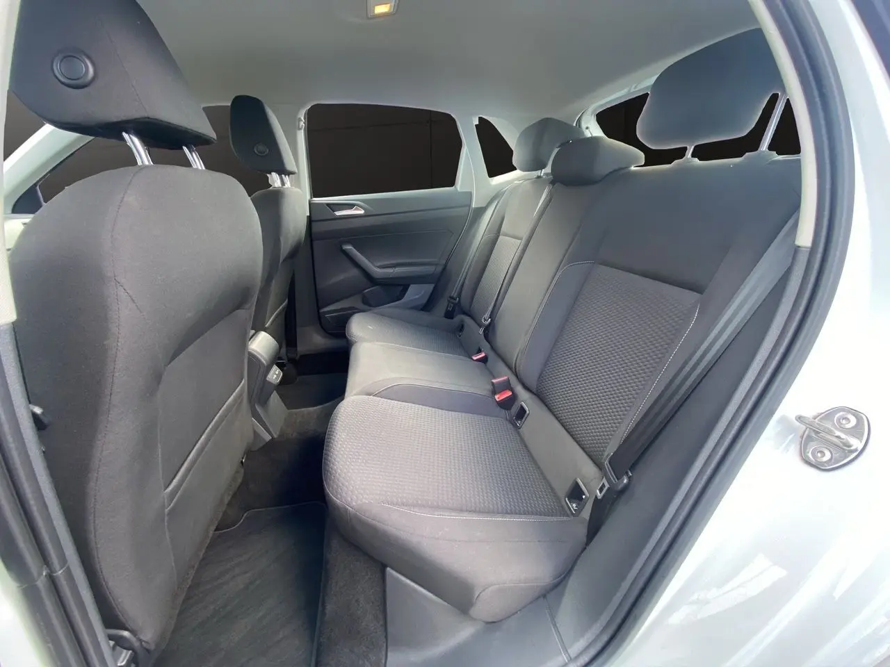 Vue intérieure côté droit sur la banquette arrière noire en tissu d'une Volkswagen Polo blanche 2020 cinq portes.