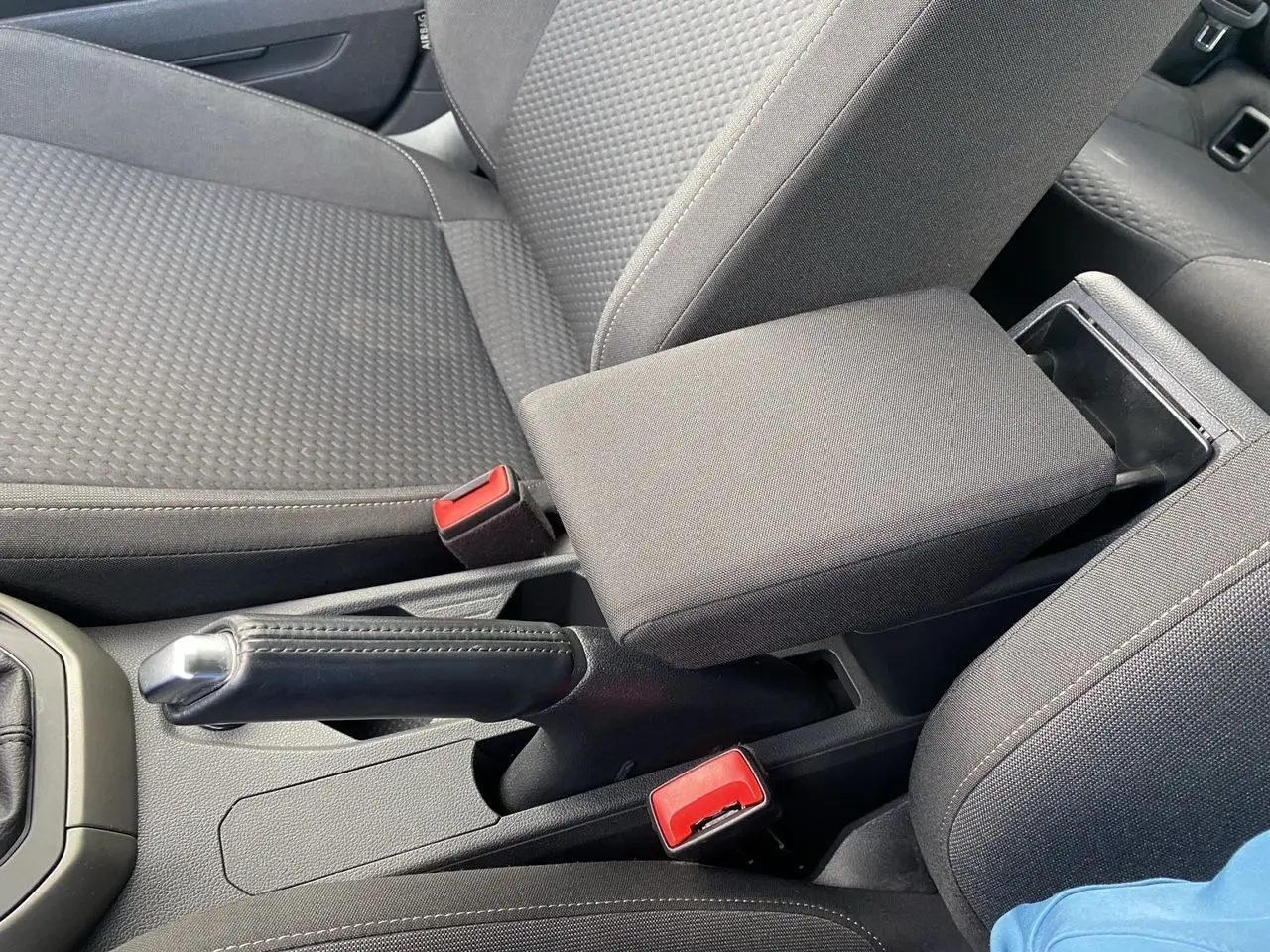 Gros plan sur l'accoudoir central et les sièges en tissu noir de l'intérieur d'une Volkswagen Polo 2020.