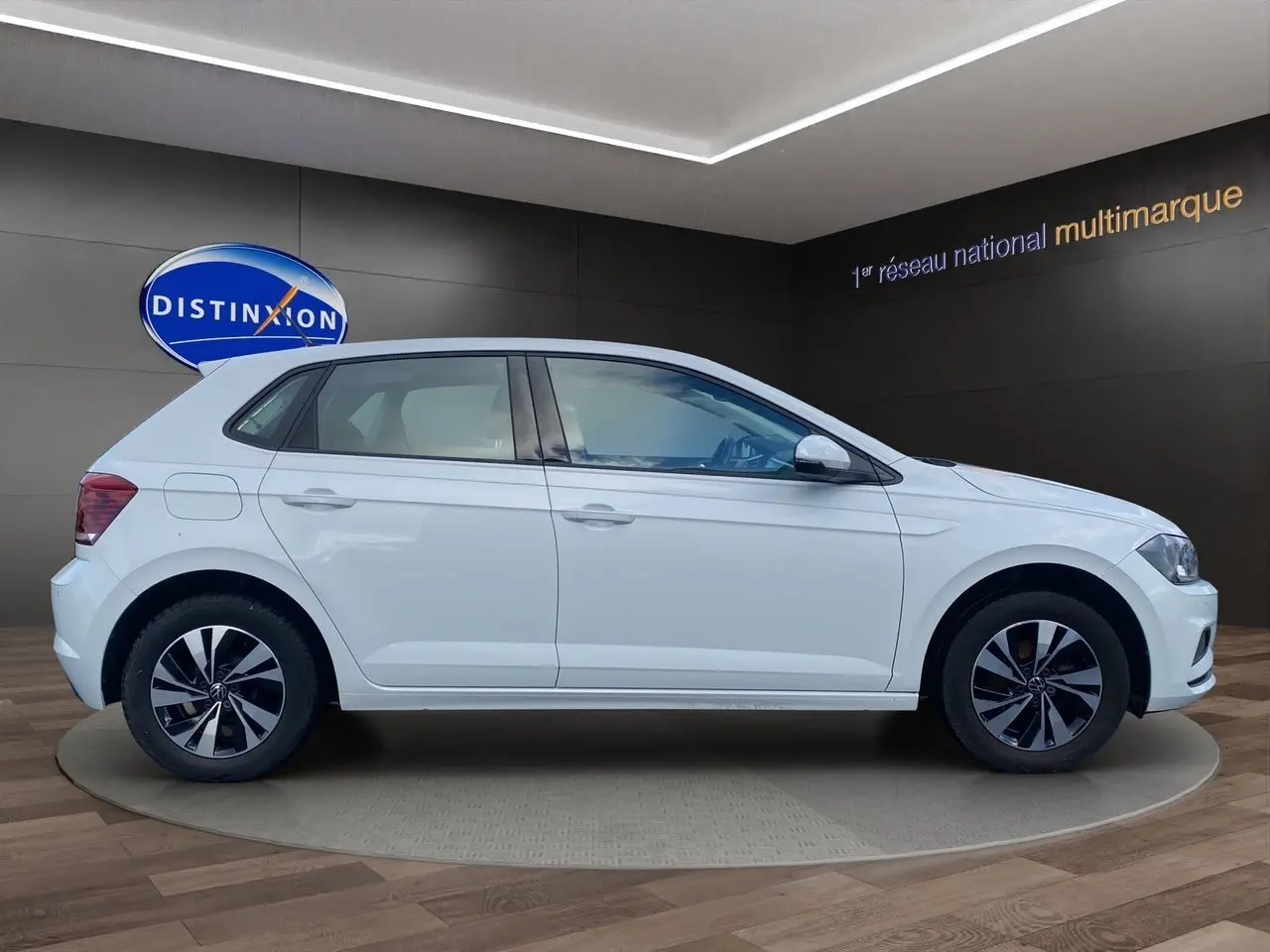 Profil droit d’une Volkswagen Polo blanche Pure 5 portes, avec jantes alliage noires et grises, en showroom.