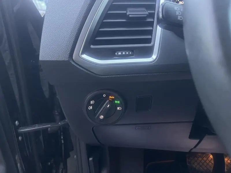 Détail du tableau de bord côté gauche du SEAT Ateca noir, montrant la commande des phares et la sortie d'air.