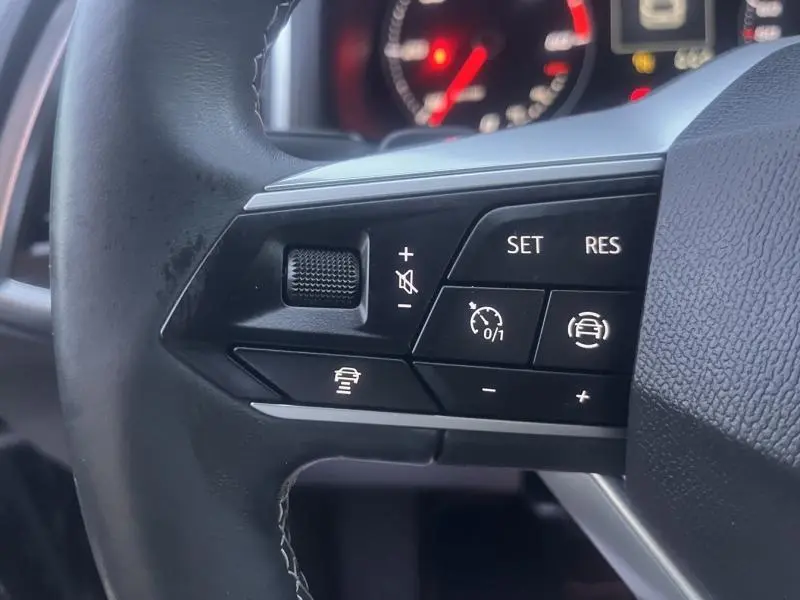 Gros plan sur les commandes multifonctions noires du volant cuir du SEAT Ateca 2022, avec tableau de bord flou en arrière-plan.