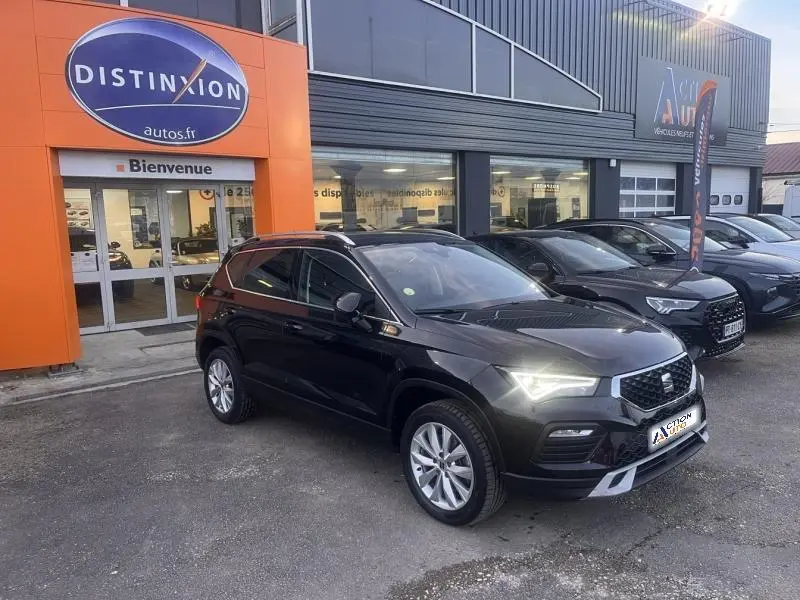 SEAT Ateca noir Magique Métal en 3/4 avant droit, phares LED allumés, devant un showroom Distinxion.