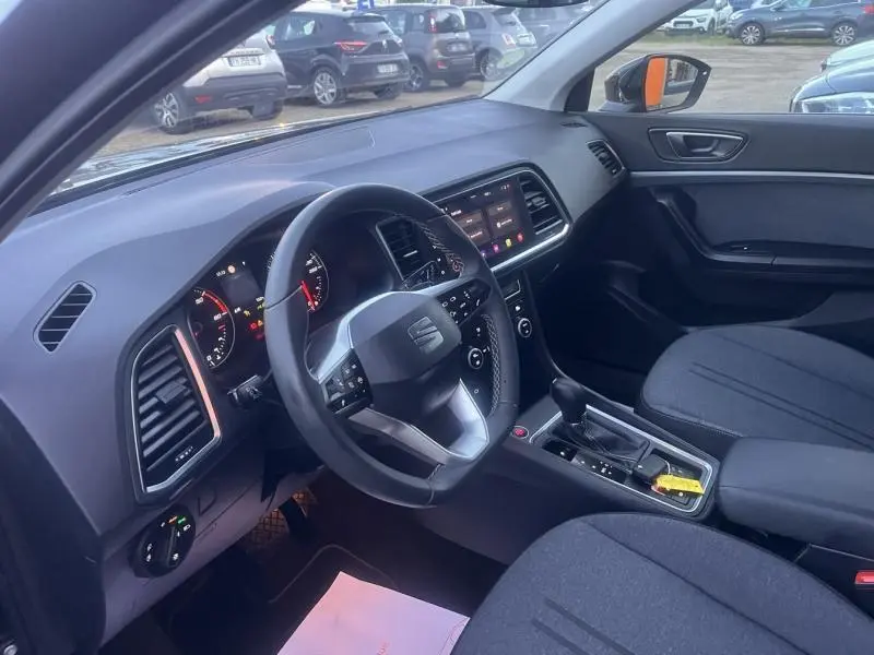 Vue intérieure côté conducteur du SEAT Ateca 2022 noir, volant cuir multifonctions et console centrale avec levier de vitesse.