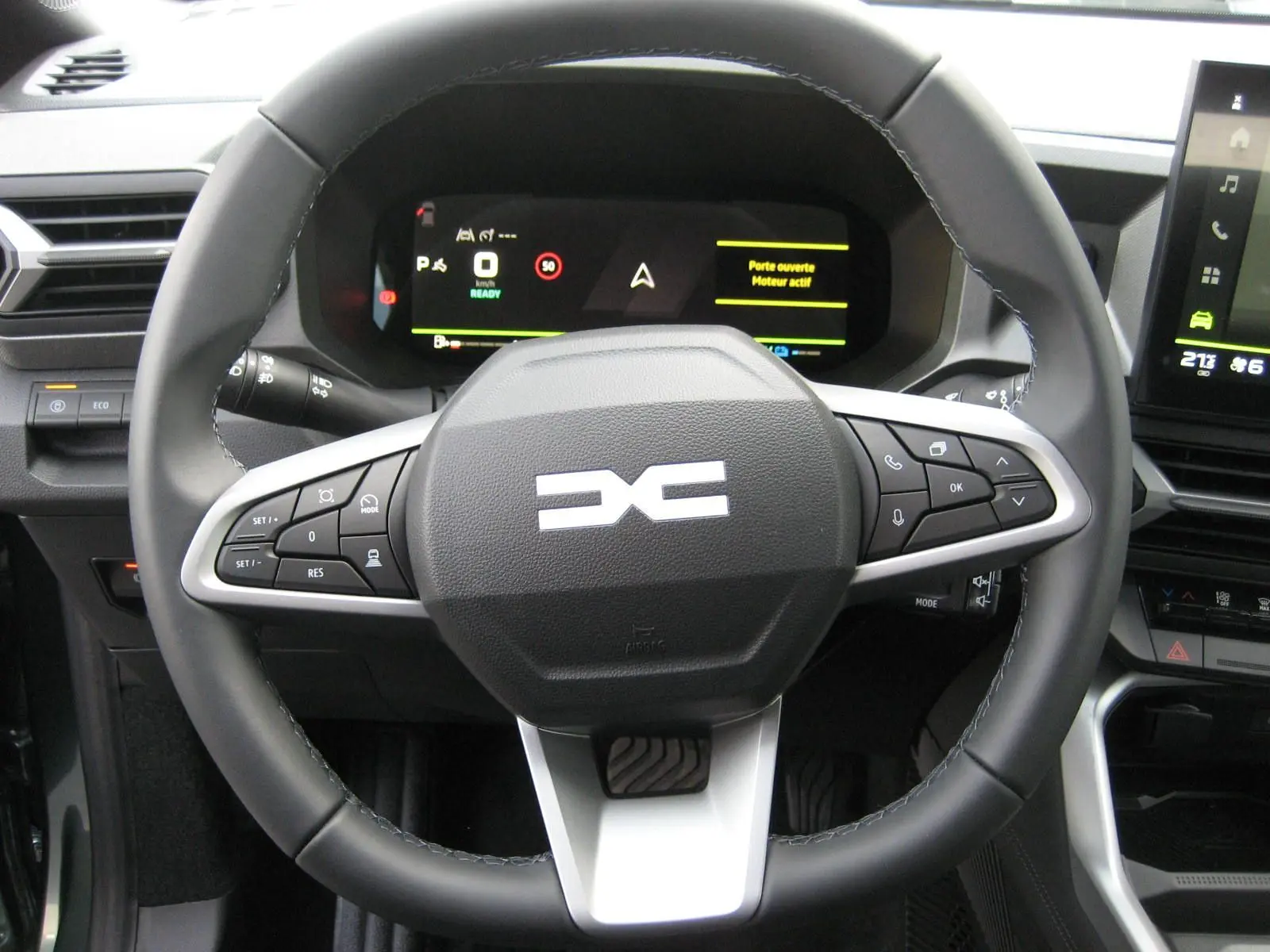 Vue rapprochée du volant noir avec logo DACIA stylisé et tableau de bord numérique du Dacia Bigster gris schiste 2026.