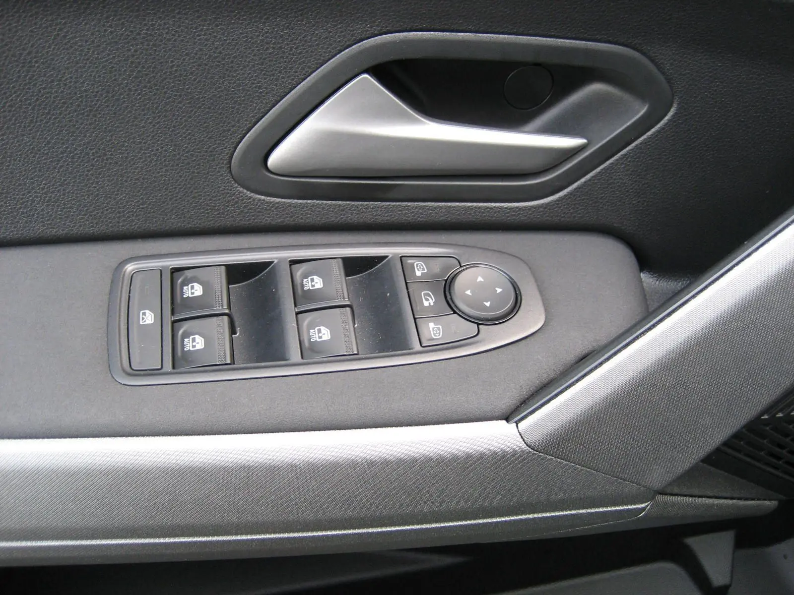 Gros plan sur la commande des vitres et la poignée intérieure côté gauche du Dacia Bigster gris schiste.
