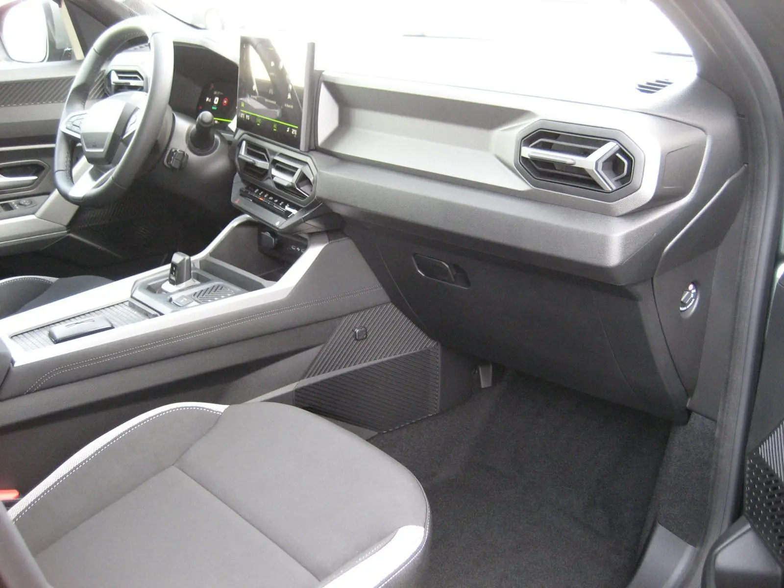 Vue intérieure côté passager du tableau de bord et console centrale du Dacia Bigster 1.8 Hybrid gris schiste, finition Journey.