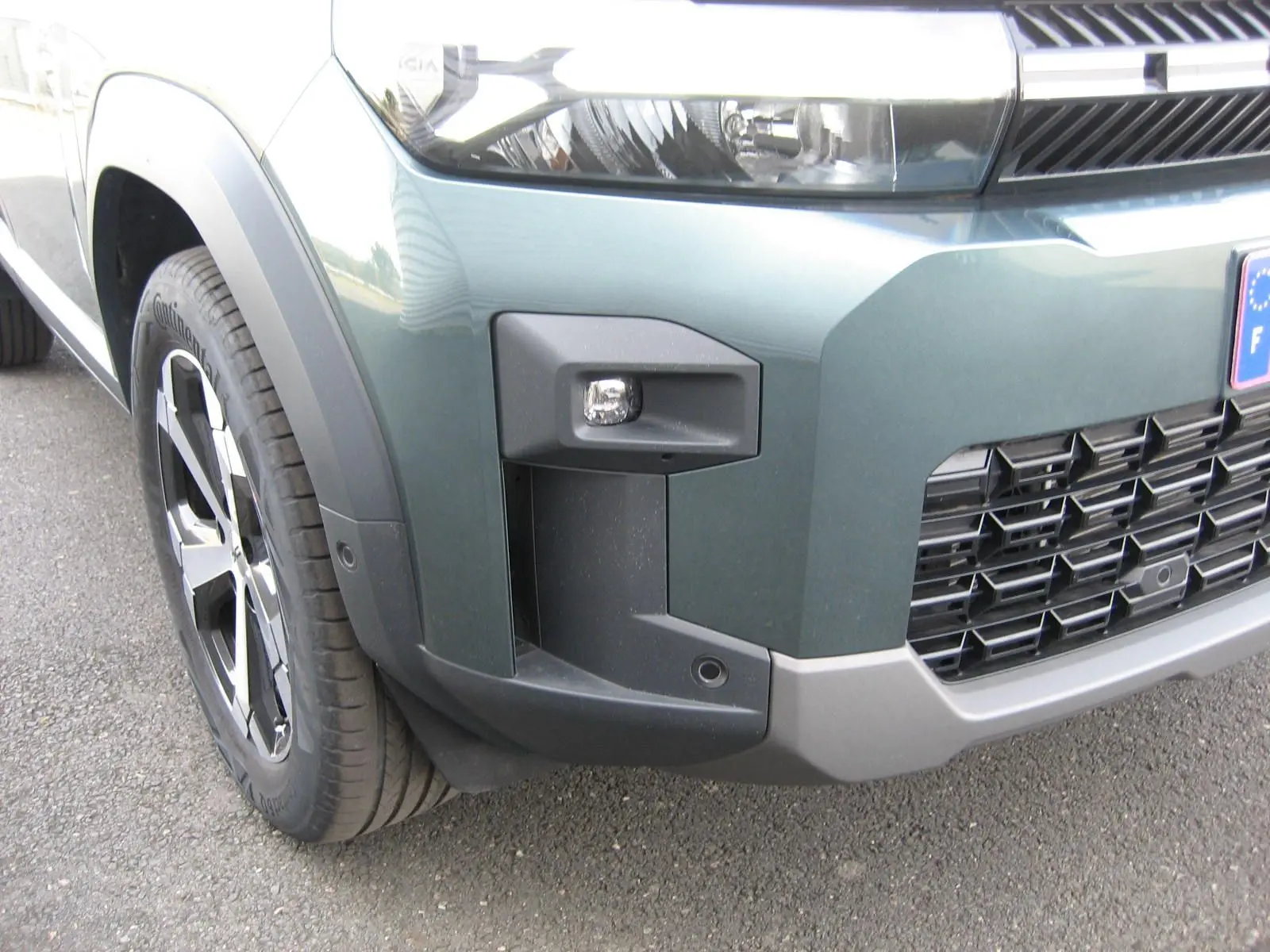 Gros plan sur l’avant droit gris schiste du Dacia Bigster 2026, mettant en valeur le phare et la calandre noire.