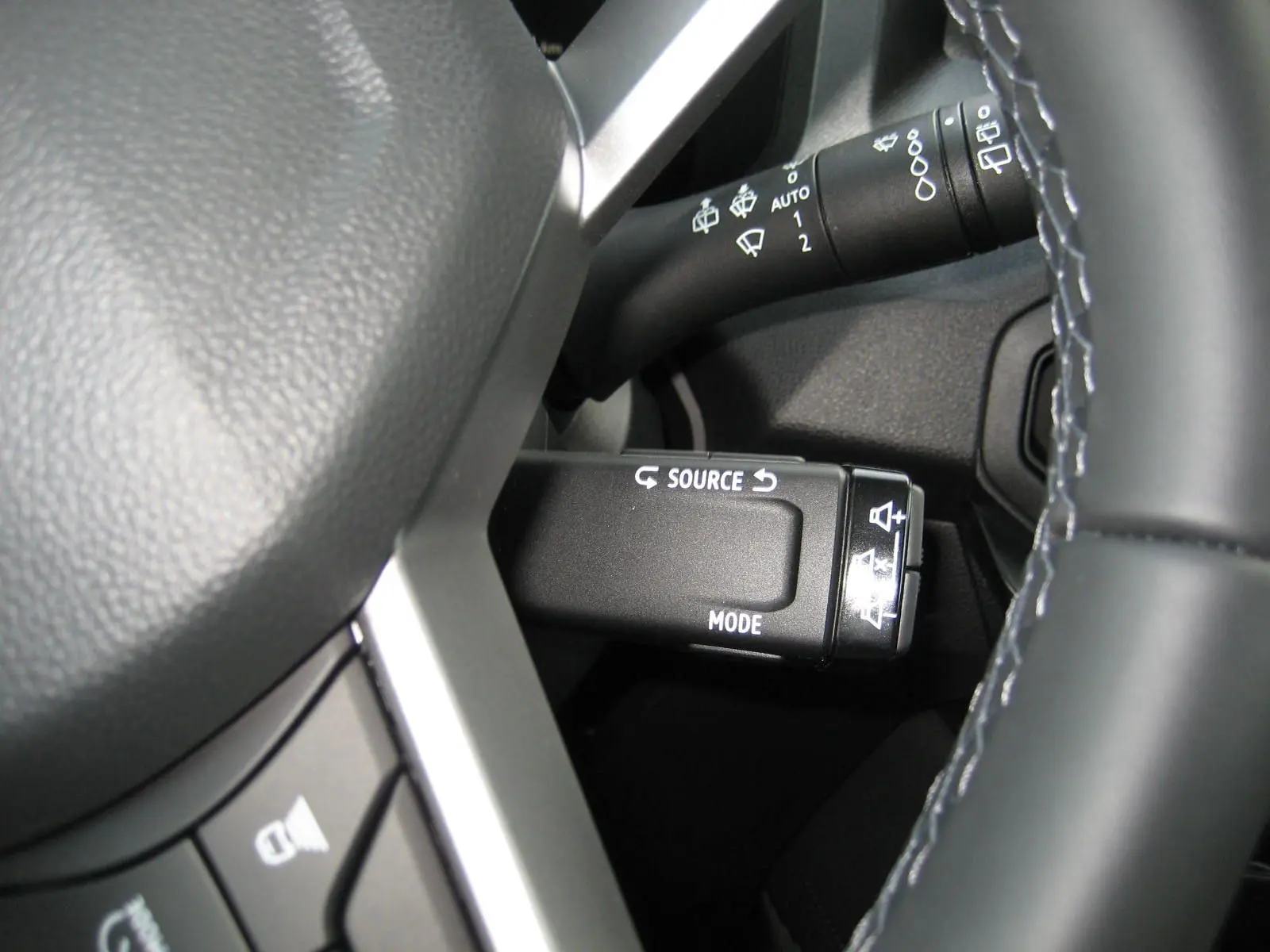 Gros plan sur la commande multimédia au volant du Dacia Bigster gris schiste, avec détails des boutons source et mode.