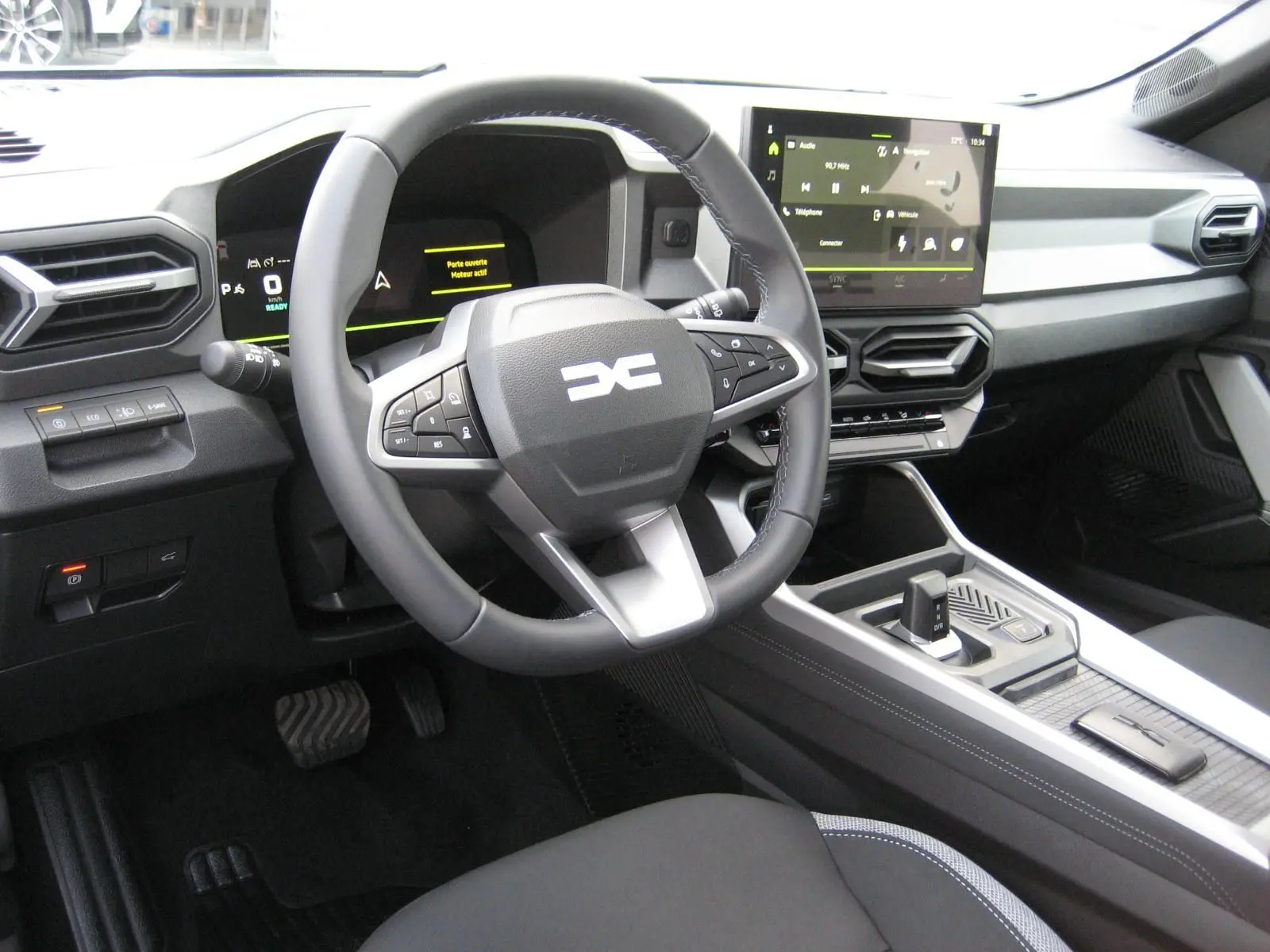 Vue intérieure du poste de conduite du Dacia Bigster 2026, avec volant multifonction et écran tactile central.