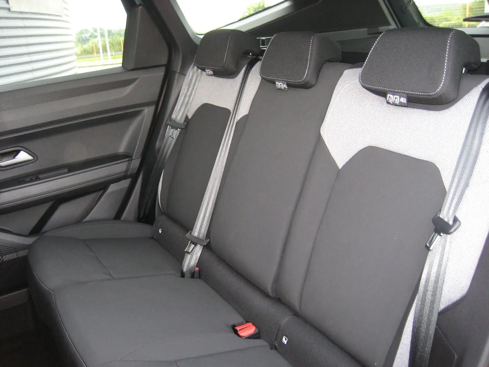 Vue intérieure sur la banquette arrière du Dacia Bigster 2026, sièges bicolores gris clair et noir avec ceintures grises.