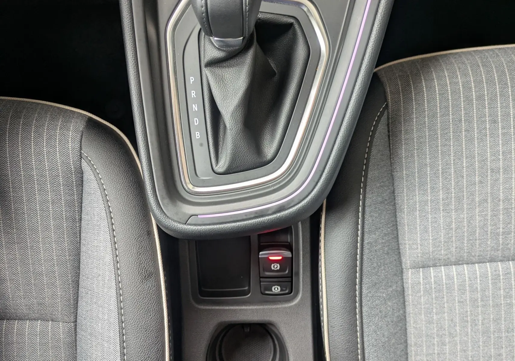 Vue plongeante sur la console centrale noire étoile métal de la Renault Clio 2025, avec levier de vitesse automatique et sièges gris.