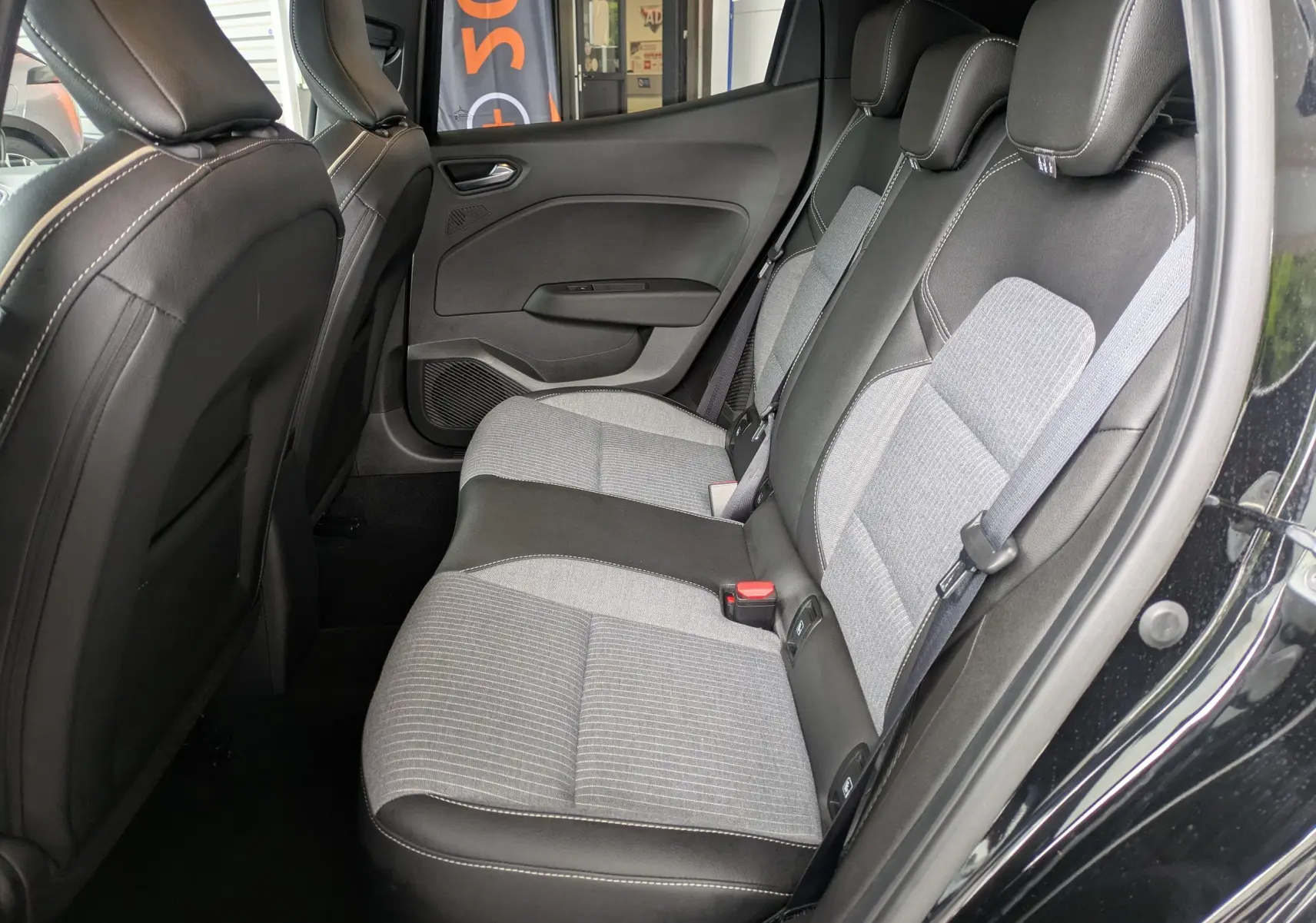 Vue latérale côté droit des sièges arrière gris clair et noir de la Renault Clio V E-TECH Full Hybrid 2025.