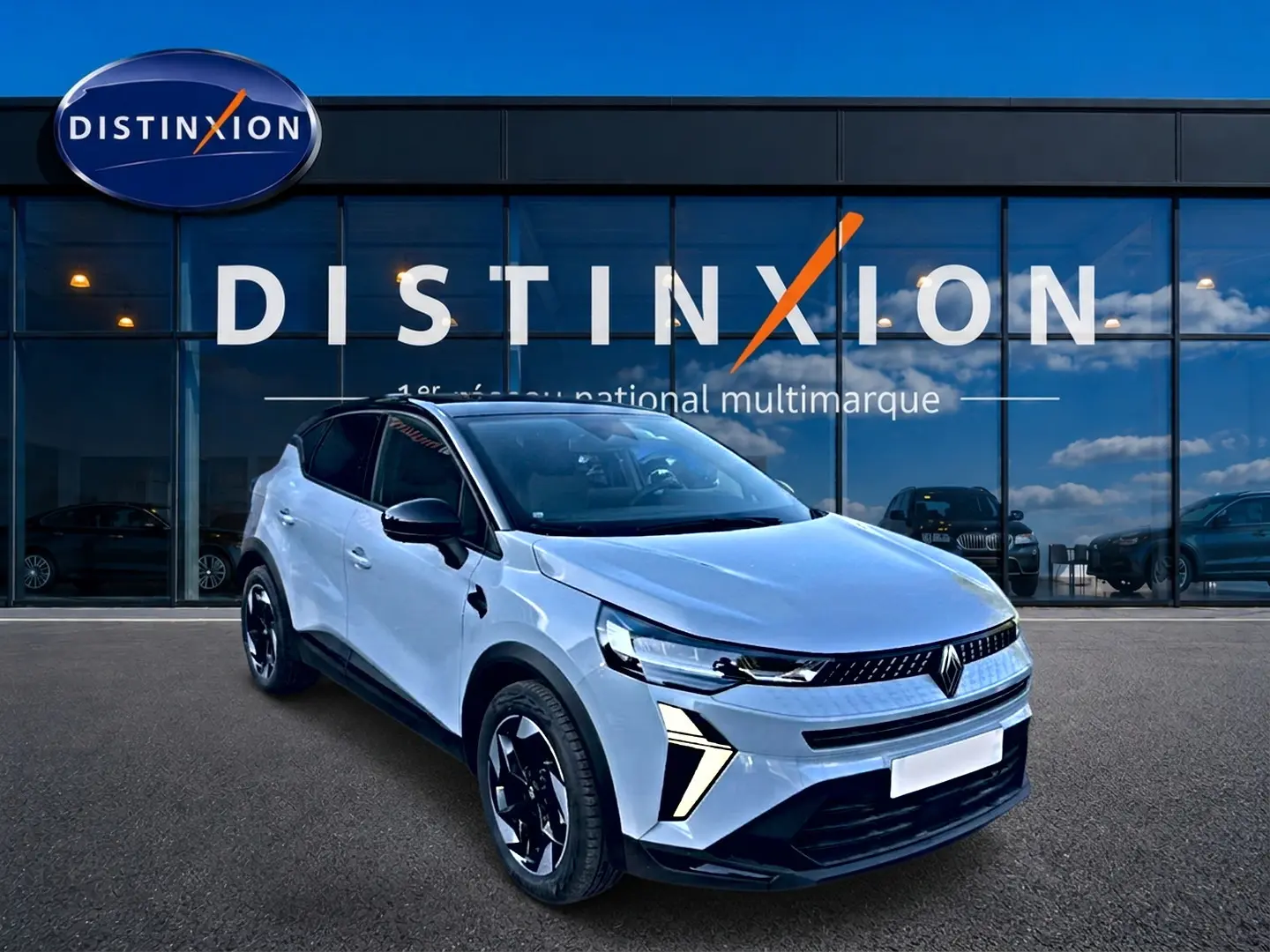 Renault Captur 2026 gris rafale en 3/4 avant, avec toit noir et jantes alu distinctives, devant showroom Distinxion.