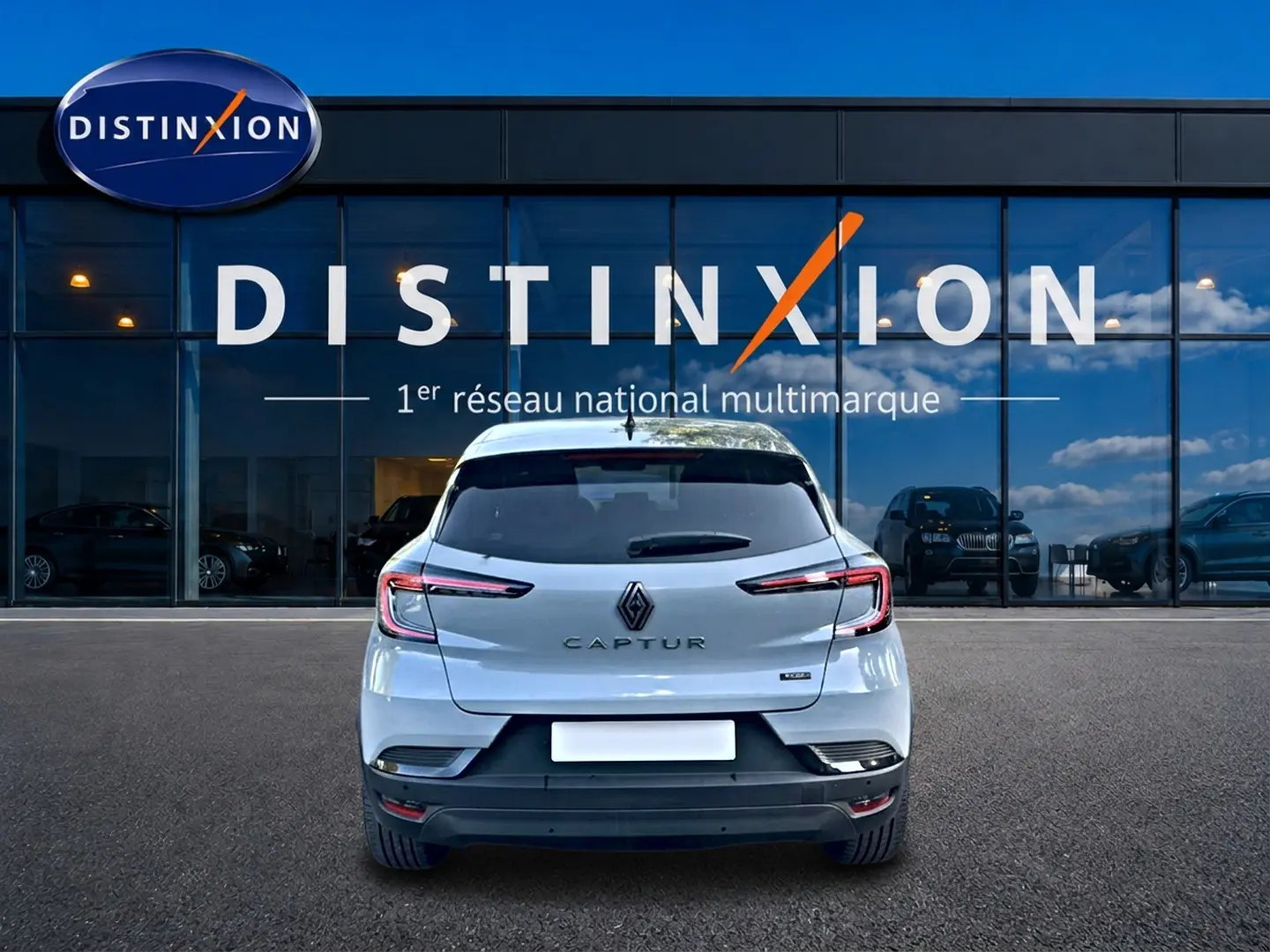 Vue arrière d'un Renault Captur gris rafale 2026 garé devant une vitrine avec logo Distinxion.