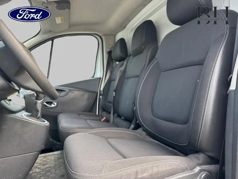 Vue intérieure côté conducteur du Renault Trafic Fourgon 2019, sièges noirs avec coutures blanches et volant multifonction.