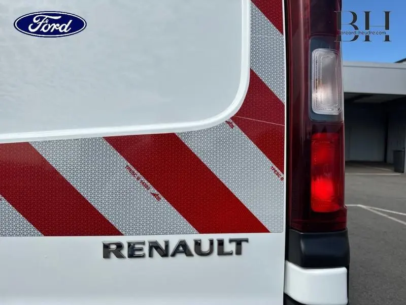 Gros plan sur l'arrière droit blanc glacier du Renault Trafic avec bandes réfléchissantes rouges et blanches et feu arrière.