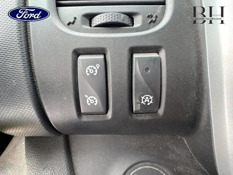 Gros plan sur les commandes de régulateur de vitesse et arrêt auto moteur d’un Renault Trafic blanc Glacier.