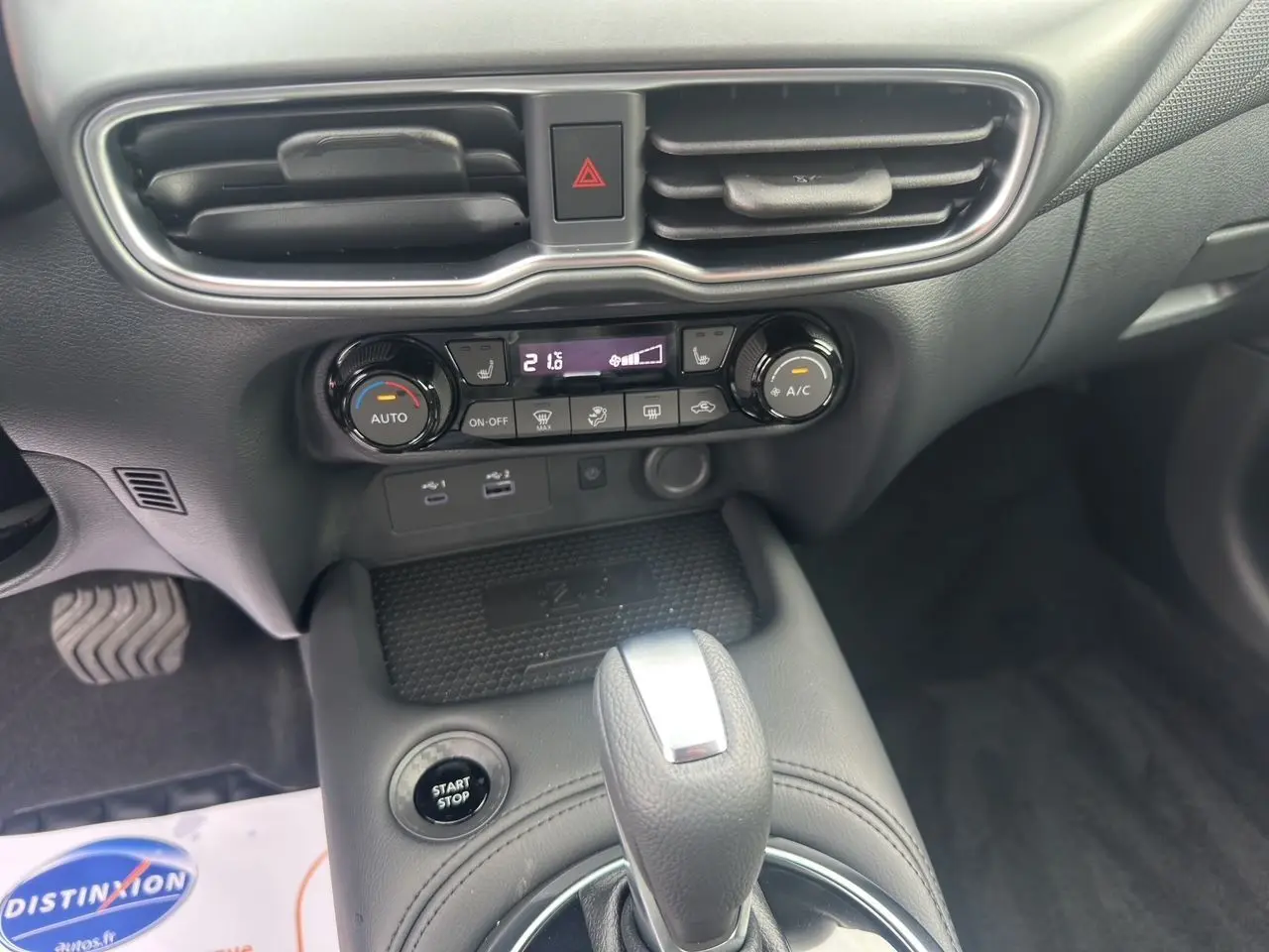 Vue intérieure centrée sur la console centrale du Nissan Juke 2025, montrant la boîte auto et les commandes de climatisation.