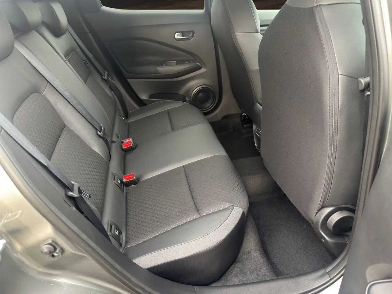 Vue intérieure arrière côté gauche du Nissan Juke 2025 gris squale, montrant les sièges arrière en tissu et cuir.