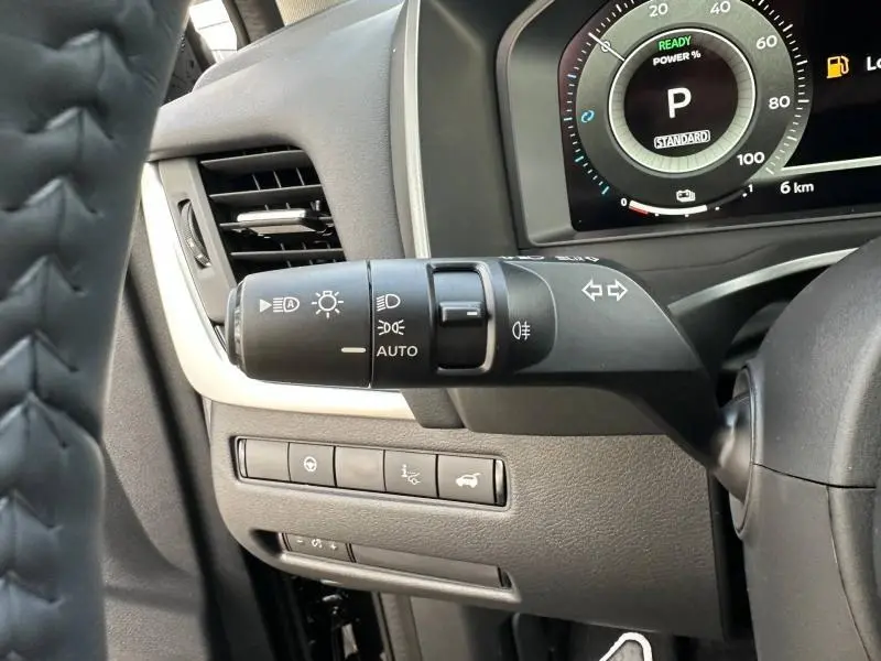 Gros plan sur la commande des phares et clignotants à gauche du volant dans le tableau de bord noir du Nissan Qashqai Hybrid e-POWER 2025.
