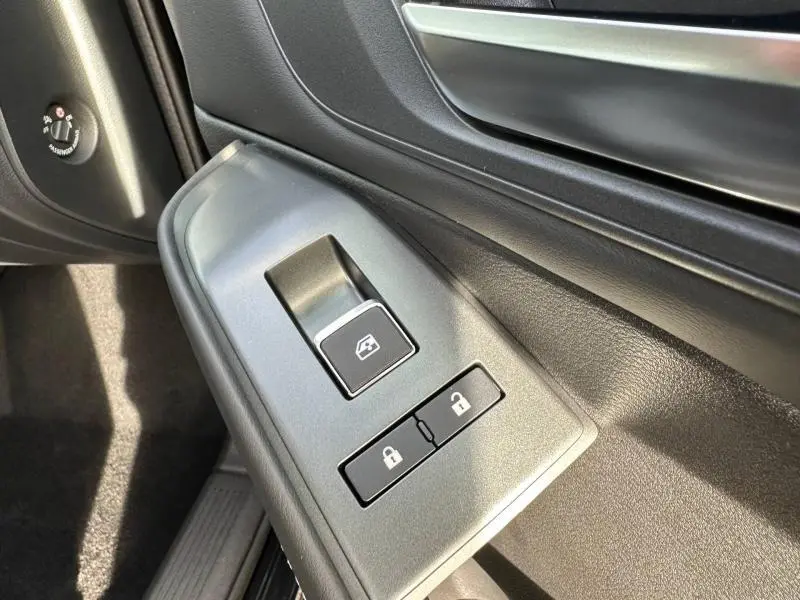 Gros plan sur les commandes de lève-vitre et verrouillage côté gauche intérieur du Nissan Qashqai Hybrid e-POWER 2025 noir Kuro.