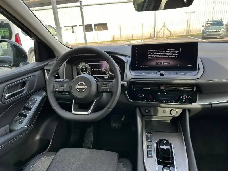 Vue intérieure du Nissan Qashqai Hybrid e-POWER 2025, tableau de bord et volant noir avec écran tactile central large.