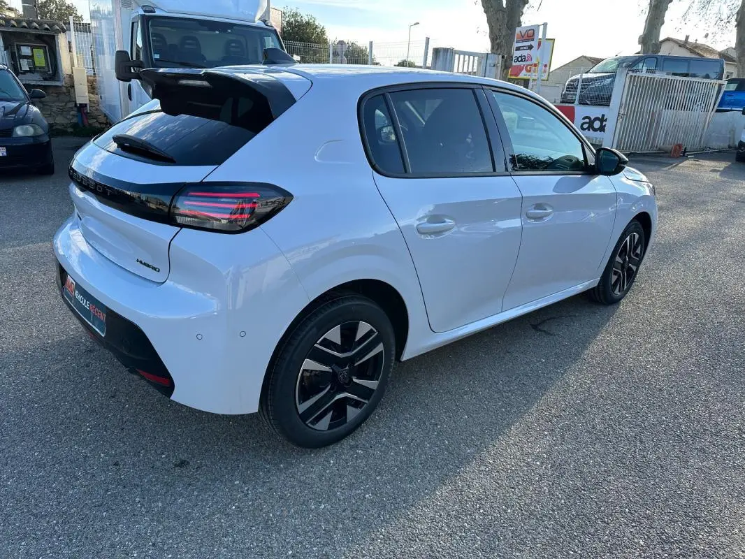 Vue 3/4 arrière droite d'une Peugeot 208 Hybrid 110 blanche avec jantes alliage noires et feux arrière LED.