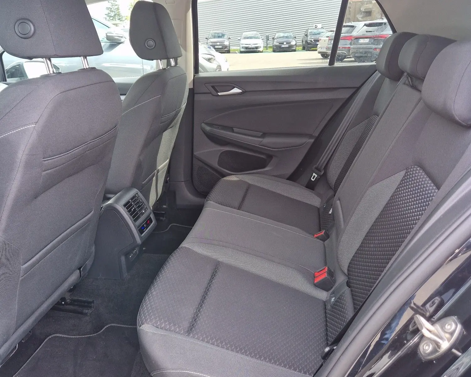 Vue intérieure côté droit sur la banquette arrière noire de la Volkswagen Golf 8 2023 avec porte ouverte.