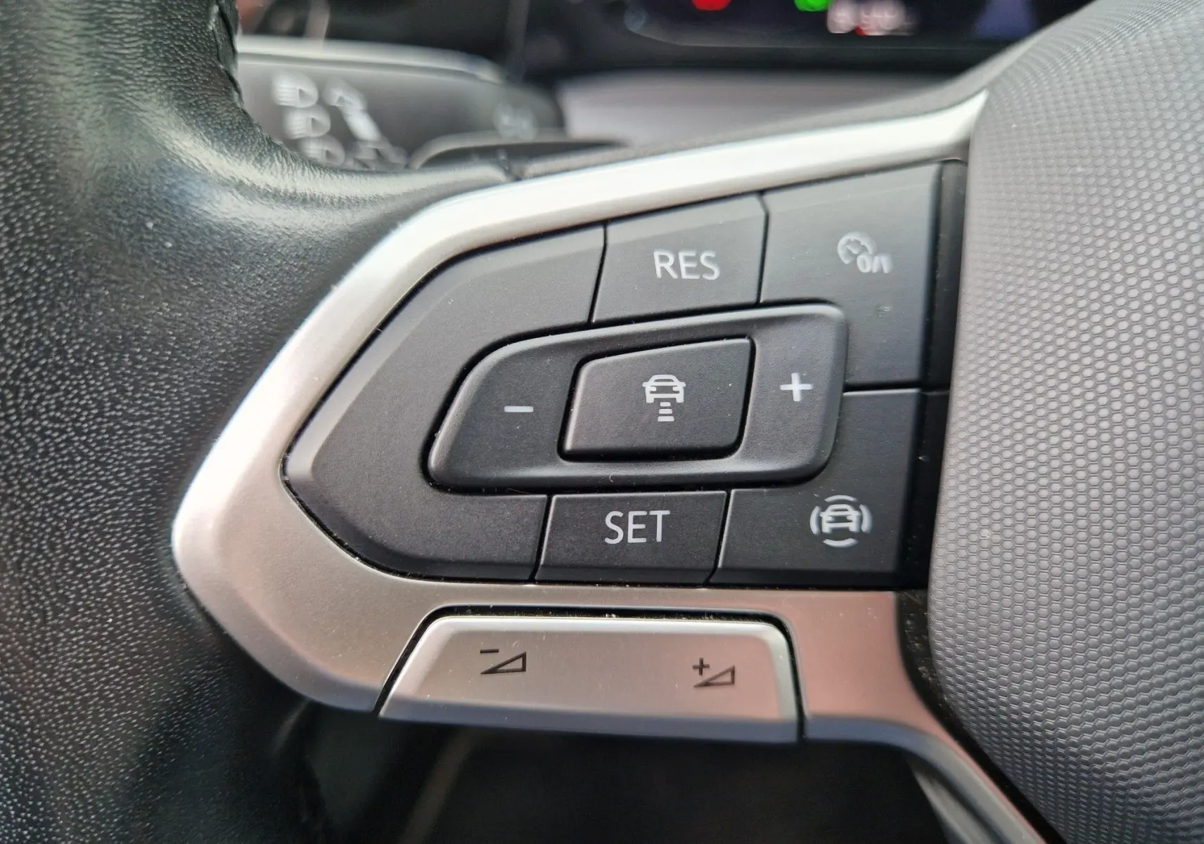Gros plan sur les commandes de régulateur de vitesse au volant d’une Volkswagen Golf 8 noire, intérieur moderne.