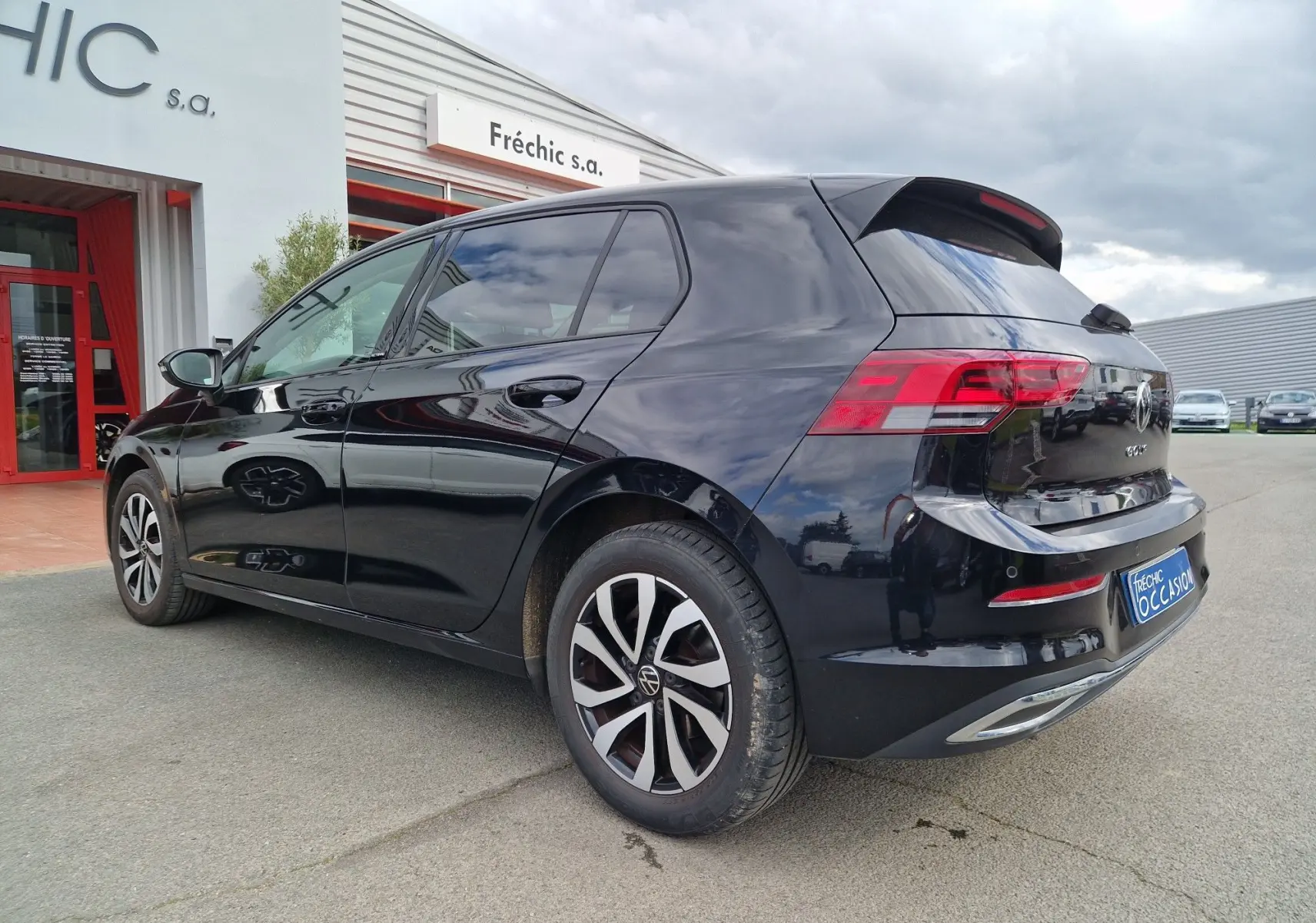 Vue 3/4 arrière droite d'une Volkswagen Golf 8 noire intense métal, avec feux arrière LED et jantes alliage distinctives.