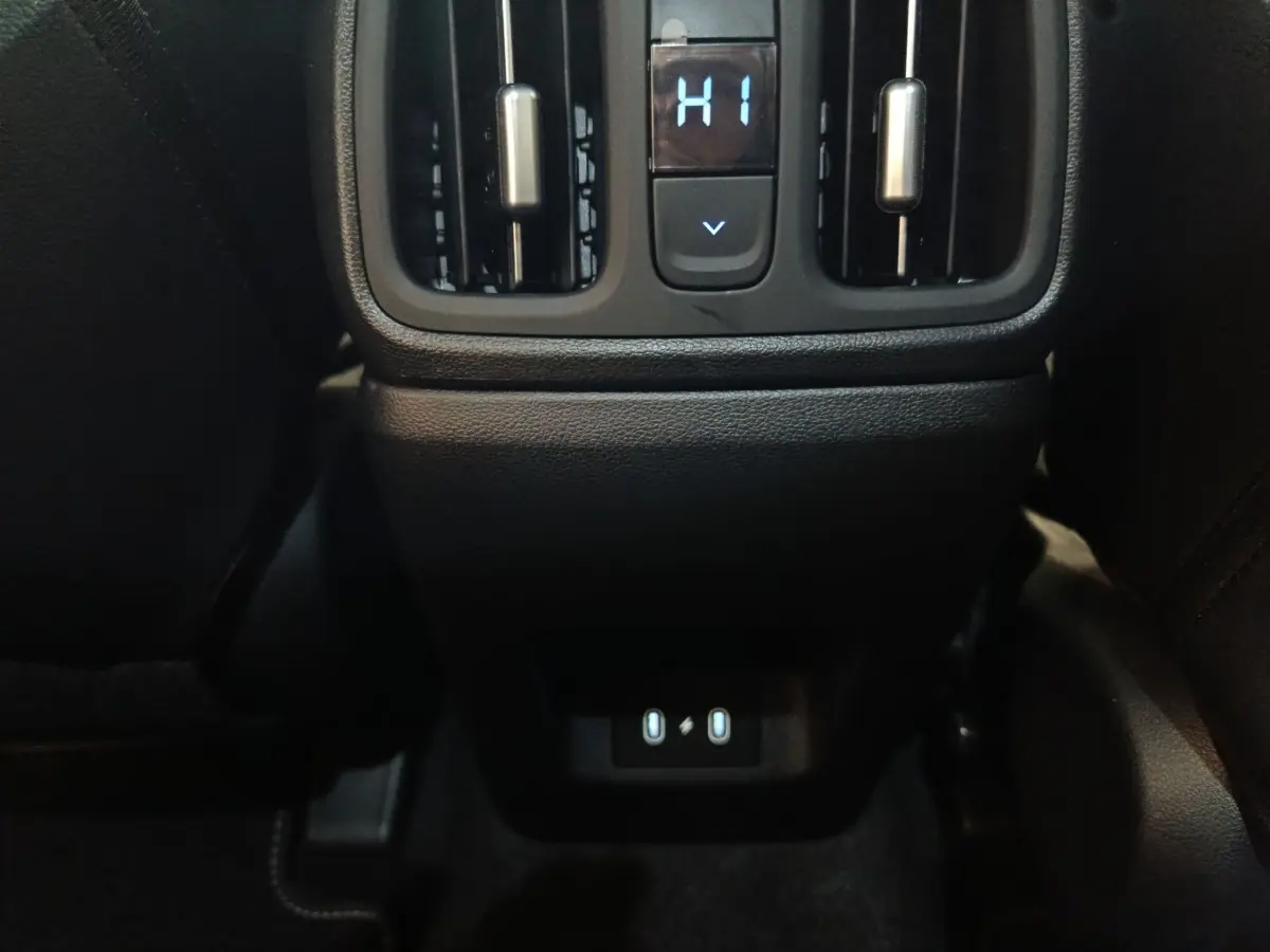 Détail de la console arrière noire du Hyundai Tucson 2025 avec commandes climatisation et ports USB éclairés.