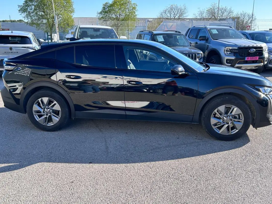 Profil côté gauche de la Peugeot 408 PHEV 180 e-EAT8 Allure noire, avec jantes alliage 17 pouces et vitres teintées.