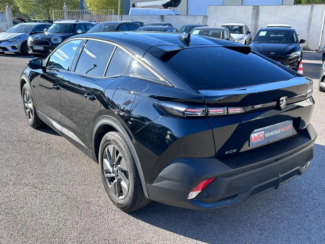 Vue 3/4 arrière droite d'une Peugeot 408 PHEV noire avec jantes alliage 17 pouces et feux arrière LED distinctifs.