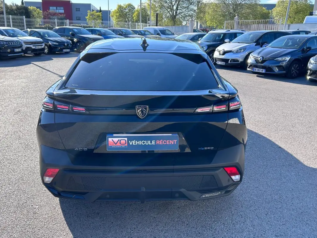 Vue arrière d'une Peugeot 408 PHEV 180 e-EAT8 Allure noire, avec feux LED caractéristiques et lunette arrière teintée.