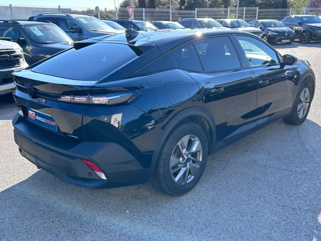 Peugeot 408 PHEV noir en 3/4 arrière droit, avec jantes alliage 17 pouces et toit incliné distinctif.