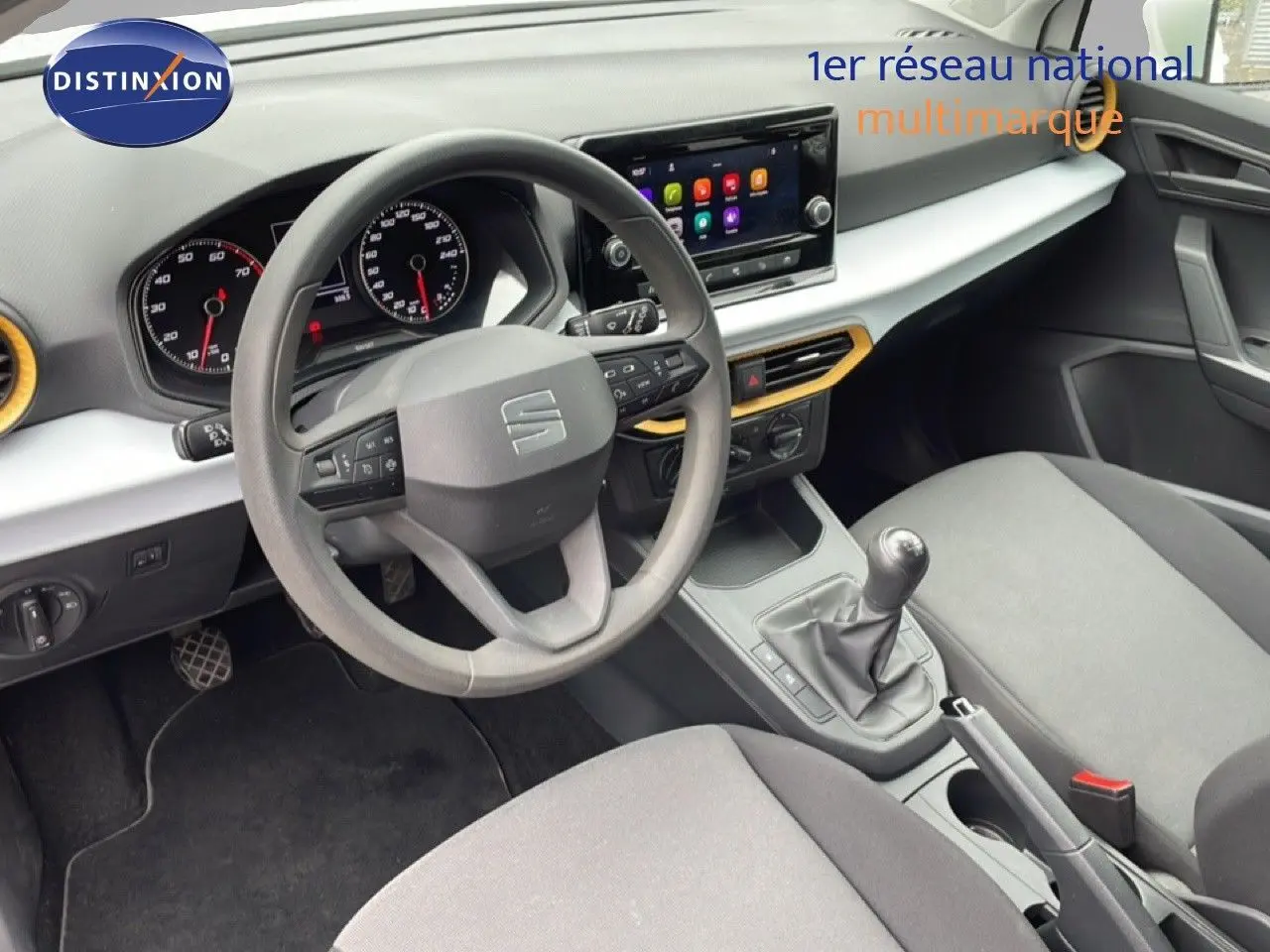 Vue intérieure côté conducteur de la SEAT Ibiza blanche, montrant le volant multifonction, la boîte manuelle et l’écran tactile central.
