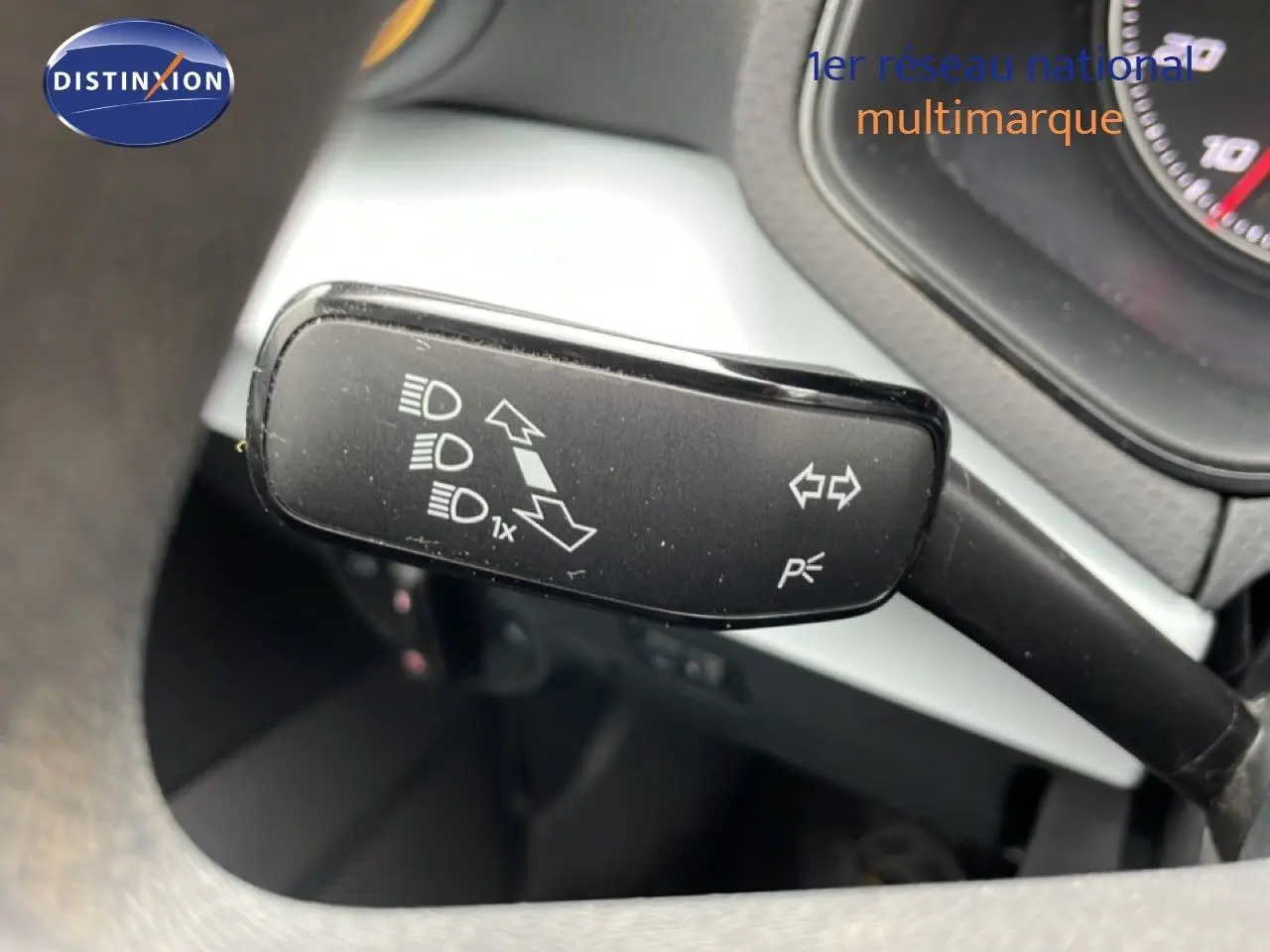 Gros plan sur la commande de clignotant à gauche du volant dans l’habitacle d’une SEAT Ibiza blanche.