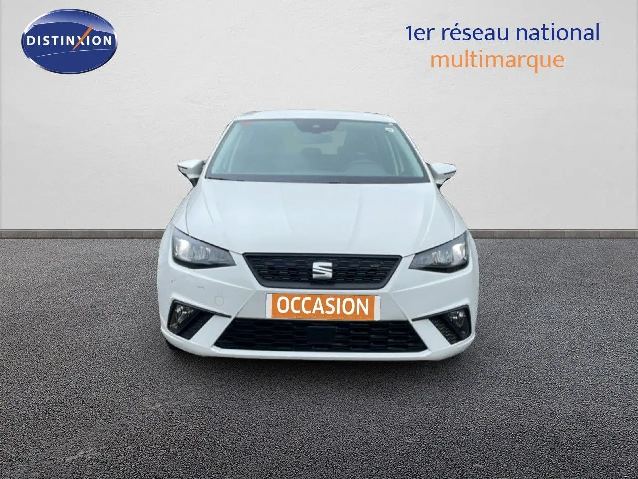 Vue avant d'une SEAT Ibiza blanche Candy avec calandre noire et plaque "OCCASION" orange sur un sol goudronné.