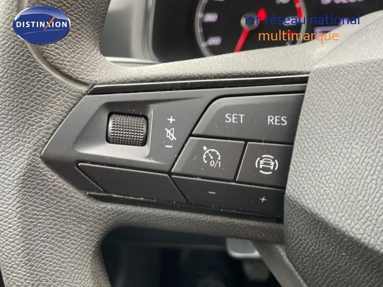 Gros plan sur les commandes au volant noir de la SEAT Ibiza blanche, mettant en valeur les boutons de régulateur de vitesse.