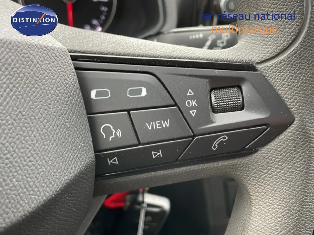 Gros plan sur les commandes au volant côté gauche de la SEAT Ibiza blanche, boutons multifonctions et molette de réglage.