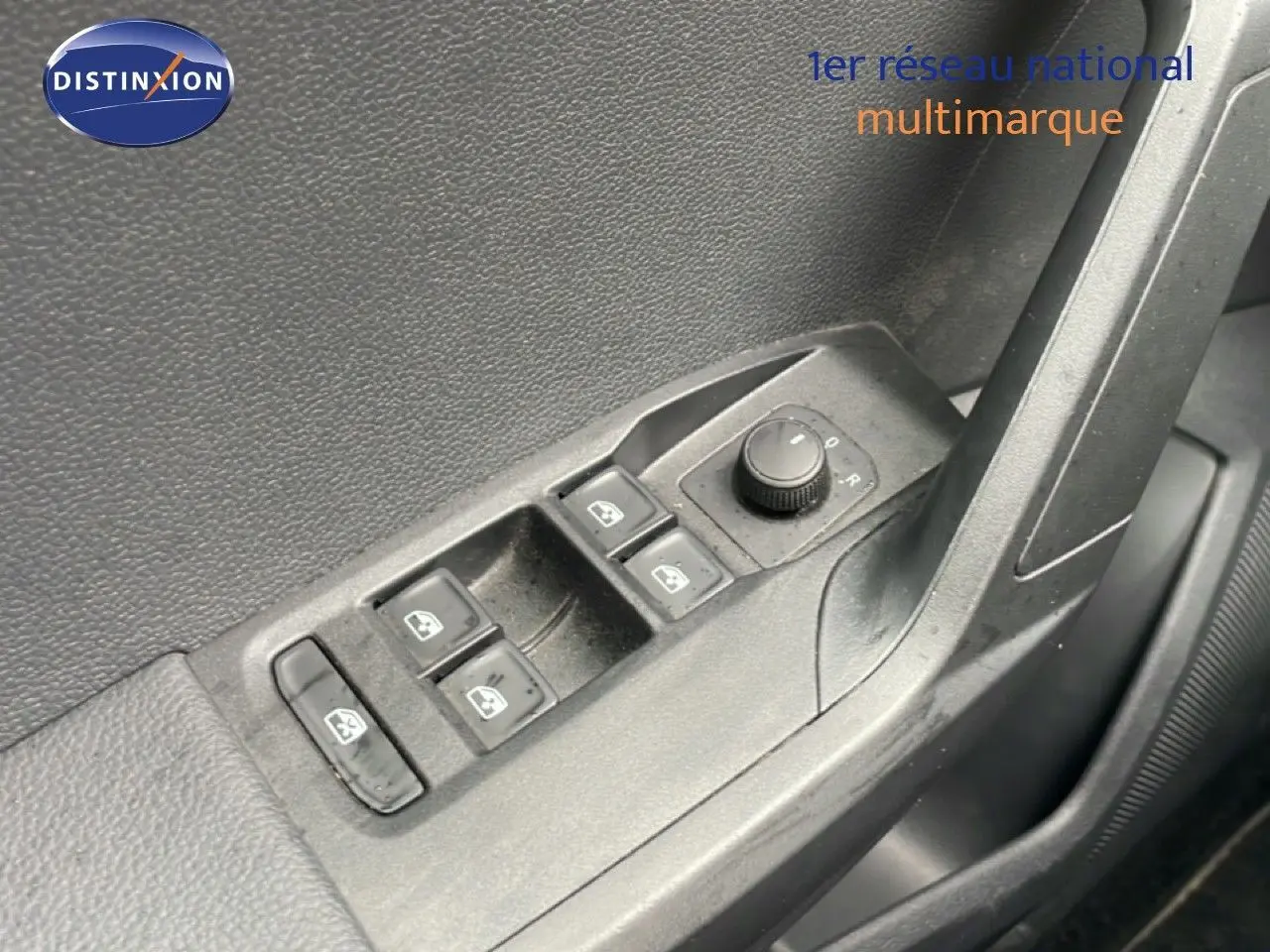 Gros plan sur les commandes de lève-vitres et réglage des rétroviseurs côté conducteur d'une SEAT Ibiza blanc candy.