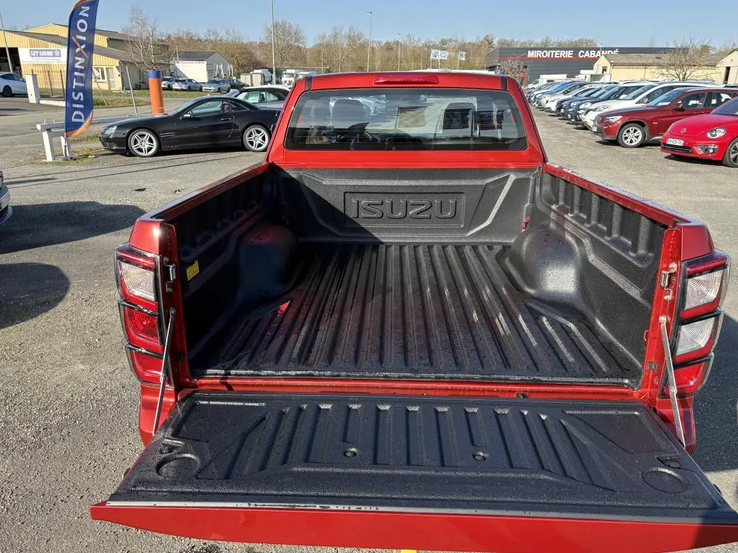 Vue arrière du pick-up Isuzu D-MAX orange 2026 avec benne ouverte et revêtement noir antidérapant.