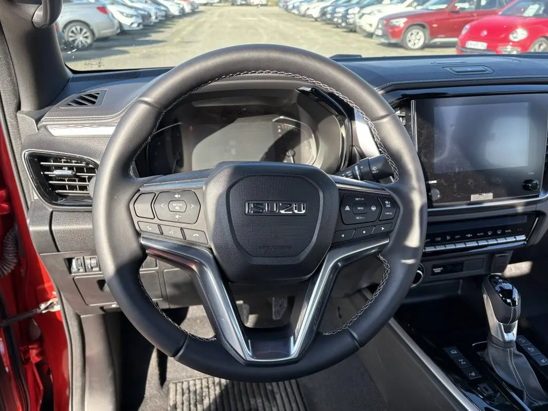 Vue intérieure centrée sur le volant multifonctions d’un Isuzu D-MAX orange avec tableau de bord et écran tactile.