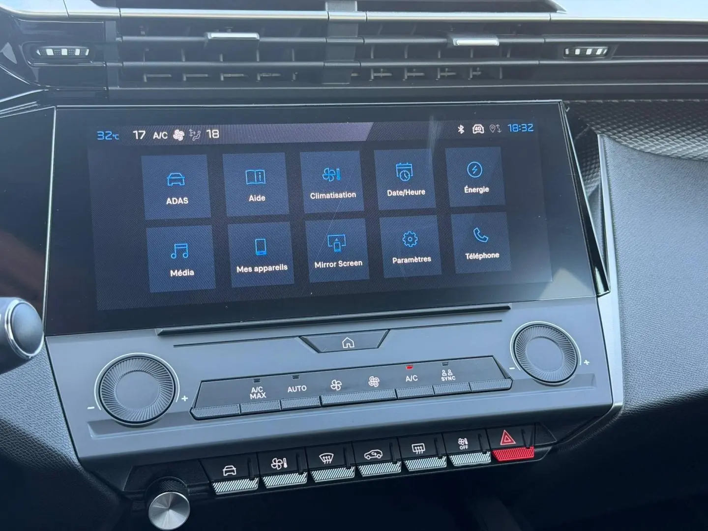 Gros plan sur l’écran tactile central et la console de climatisation de la Peugeot e-308 noire, intérieur moderne et épuré.