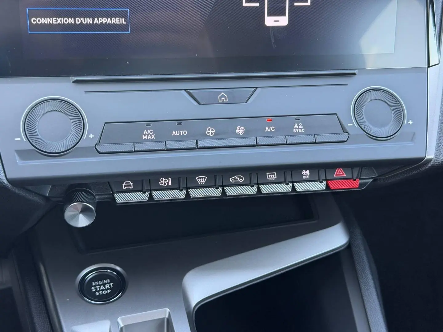 Vue rapprochée de la console centrale de la Peugeot 308 e-308 noire, montrant les commandes climatisation et bouton start/stop.