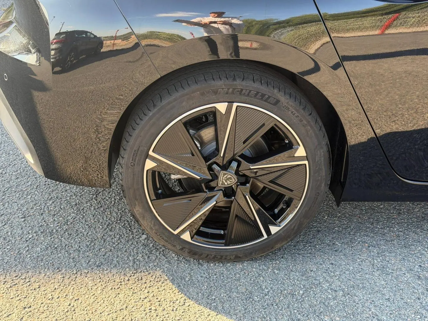 Gros plan sur la roue arrière droite noire Perla Nera d'une Peugeot e-308 2025 avec jante alu au design moderne.
