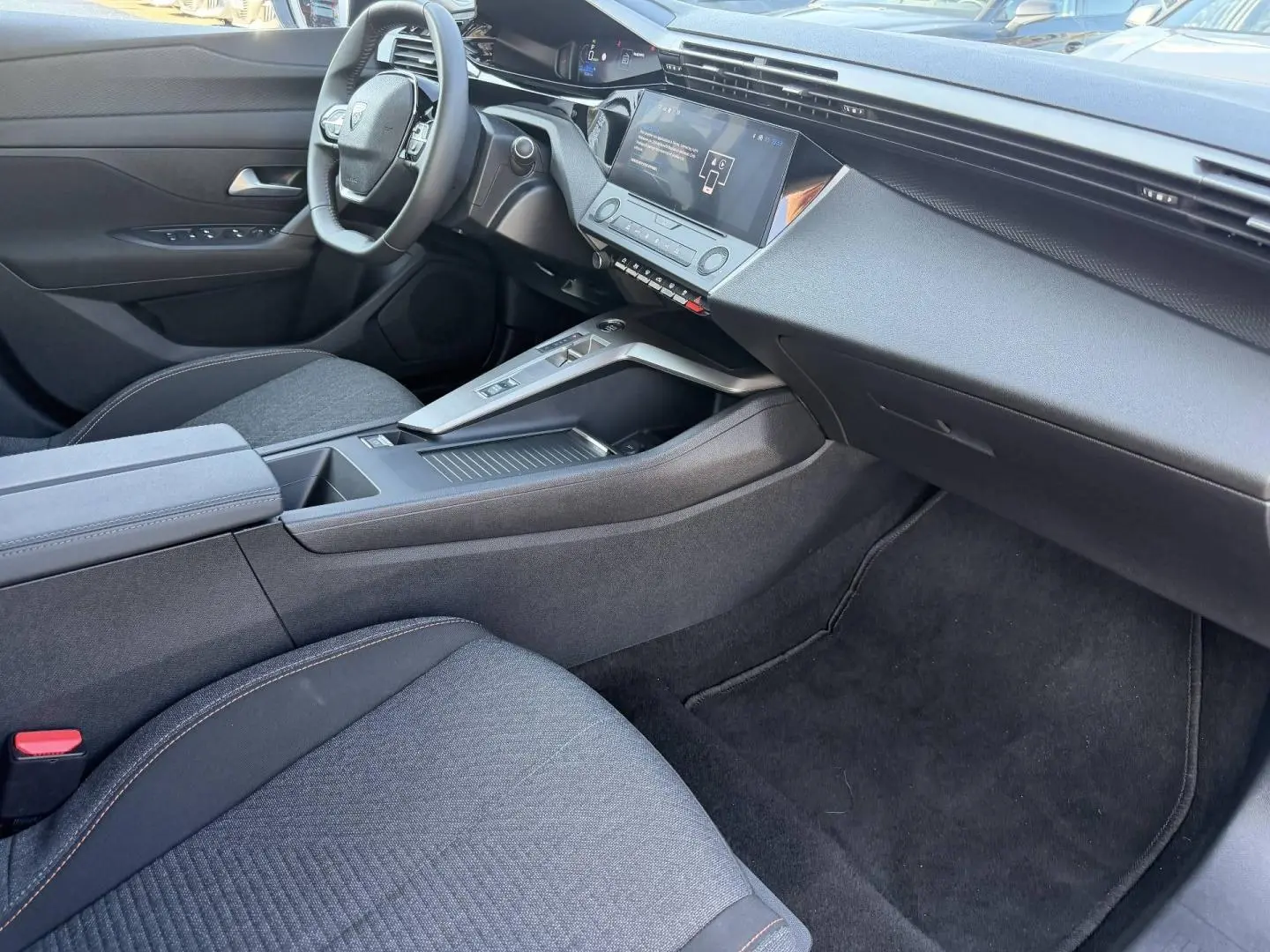 Intérieur avant droit de la Peugeot e-308 2025 noir, avec tableau de bord numérique et console centrale moderne.