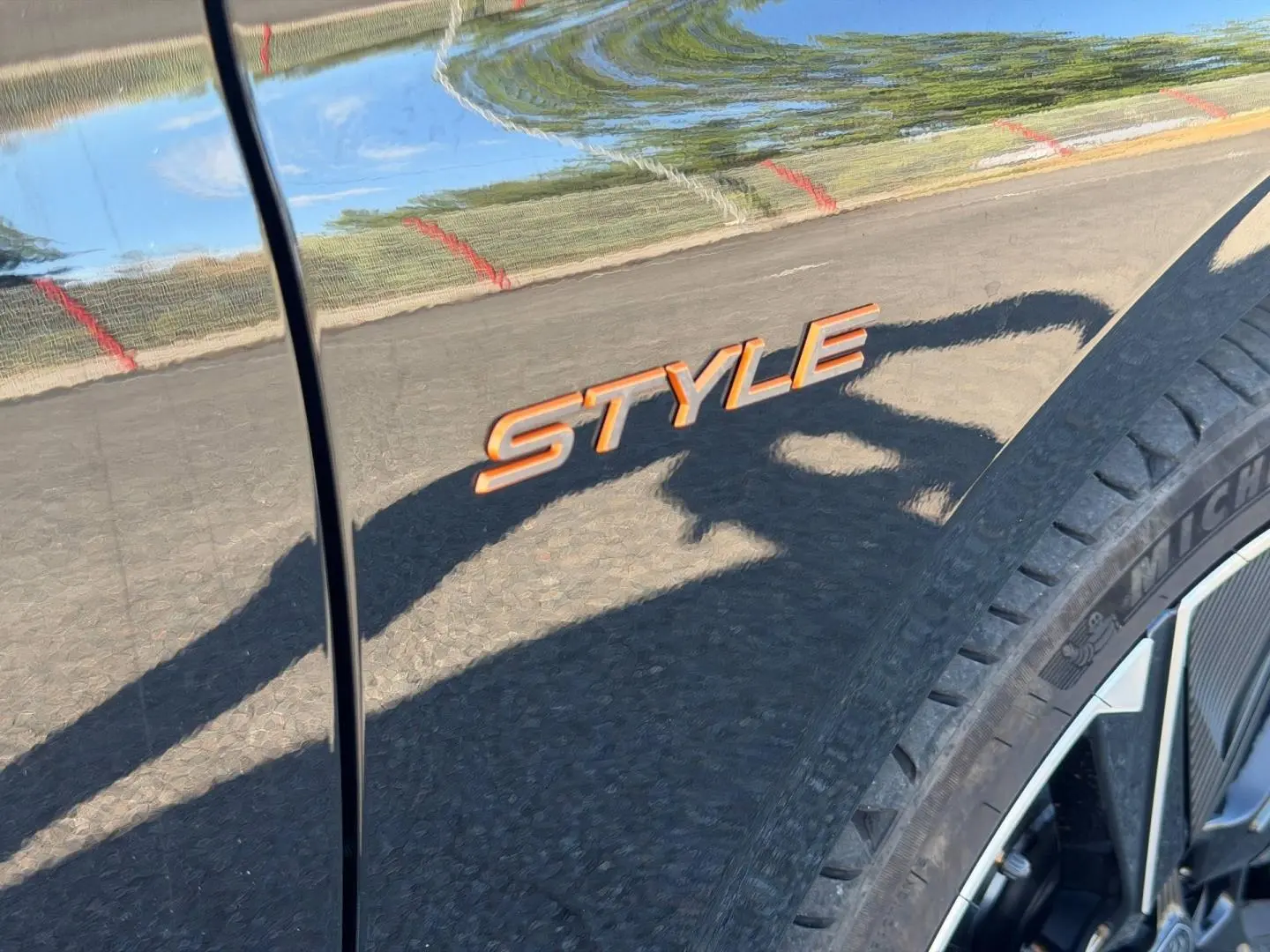 Gros plan sur l’inscription Style orange sur la carrosserie noire Perla Nera, près de la roue avant droite.